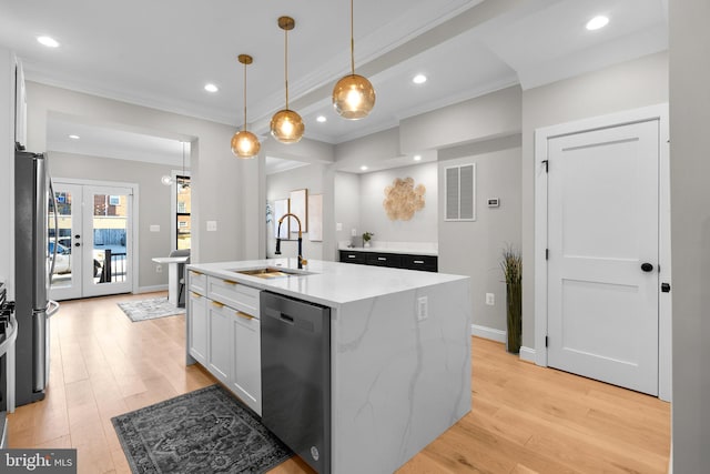 kitchen featuring sink, white cabinetry, stainless steel appliances, light stone counters, and a kitchen island with sink