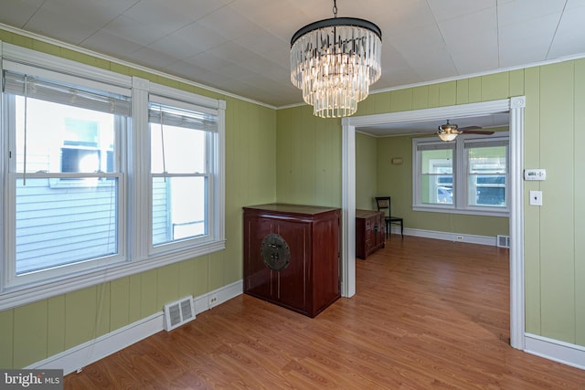 unfurnished dining area featuring crown molding, wood-type flooring, and ceiling fan with notable chandelier