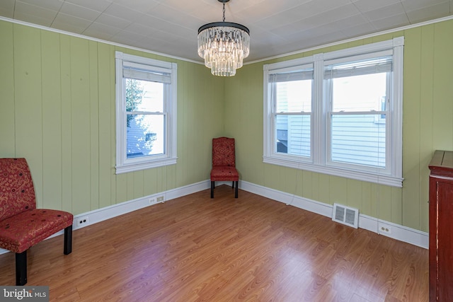 sitting room featuring crown molding, hardwood / wood-style flooring, a chandelier, and wood walls