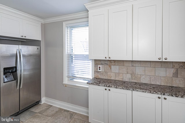 kitchen with stainless steel fridge, dark stone counters, white cabinets, crown molding, and decorative backsplash