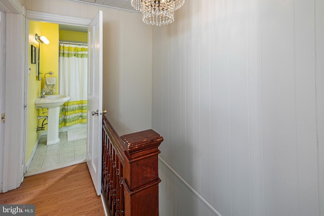 hall with sink, light hardwood / wood-style flooring, and an inviting chandelier