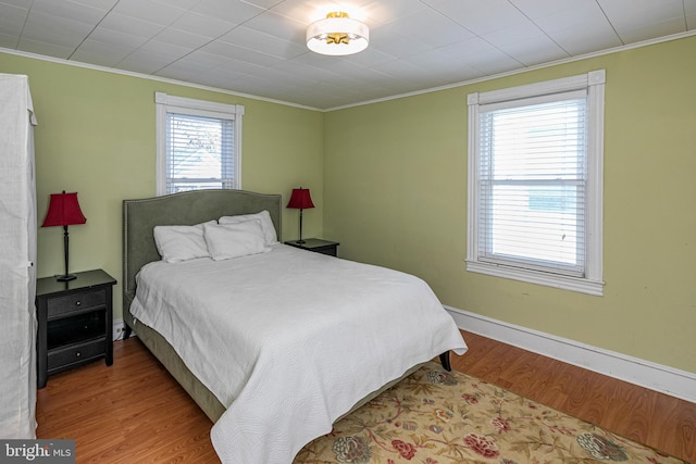 bedroom with crown molding and light wood-type flooring