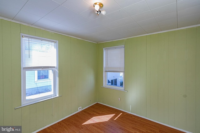 spare room with crown molding, hardwood / wood-style floors, and wooden walls