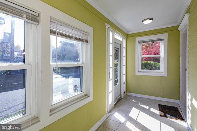 doorway to outside with ornamental molding, light tile patterned floors, and a wealth of natural light