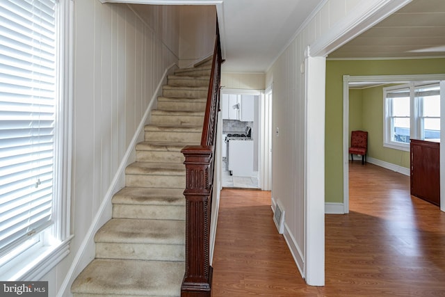 staircase featuring wood-type flooring and ornamental molding