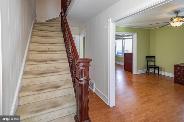 stairs with crown molding, hardwood / wood-style flooring, and ceiling fan