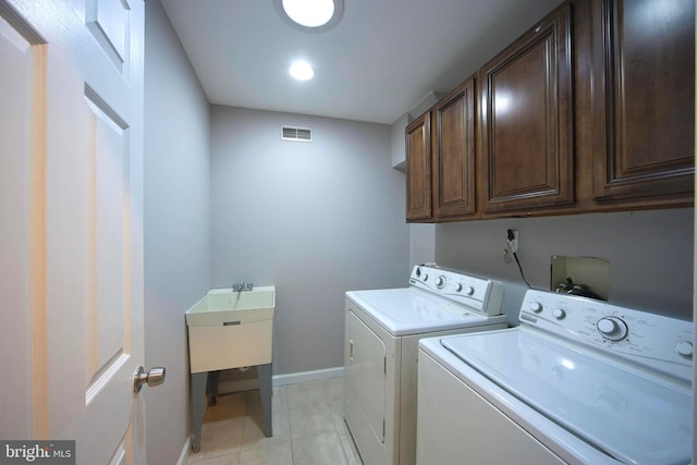 clothes washing area with washing machine and clothes dryer and cabinets