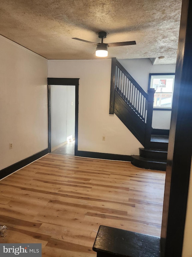 interior space with ceiling fan, wood-type flooring, and a textured ceiling