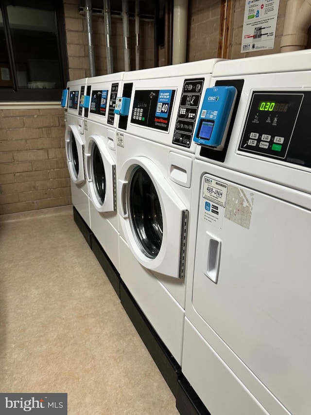 washroom with brick wall and separate washer and dryer