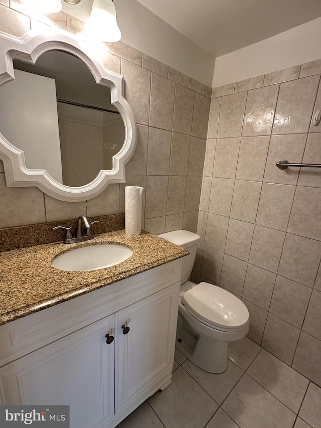 bathroom with tile walls, vanity, toilet, and tile patterned flooring