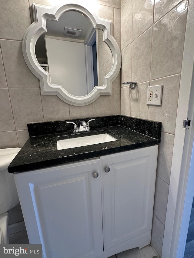 bathroom with vanity, tasteful backsplash, toilet, and tile walls