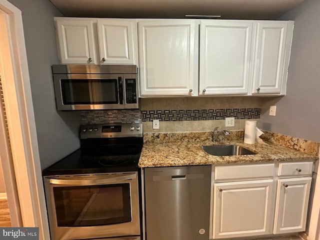 kitchen featuring sink, white cabinets, appliances with stainless steel finishes, light stone counters, and tasteful backsplash