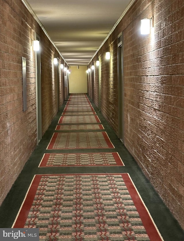 corridor with crown molding and brick wall