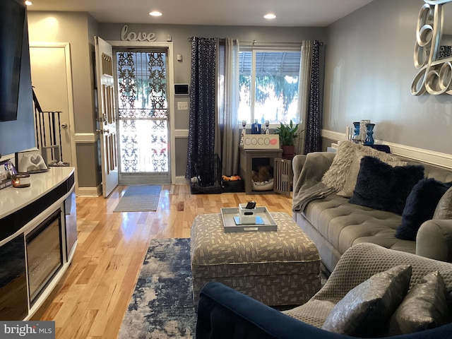 5437 Force Rd, Baltimore, MD 21206 - living area with radiator heating unit, light wood-style floors, a fireplace, recessed lighting, and stairway