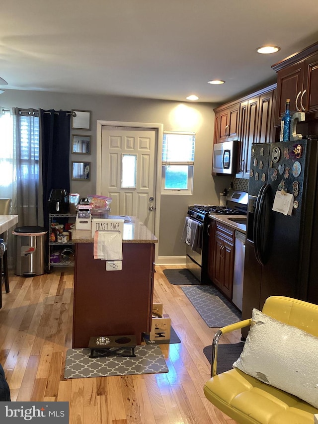 5437 Force Rd, Baltimore, MD 21206 - kitchen featuring appliances with stainless steel finishes, light wood-style flooring, a kitchen island, recessed lighting, and light stone countertops