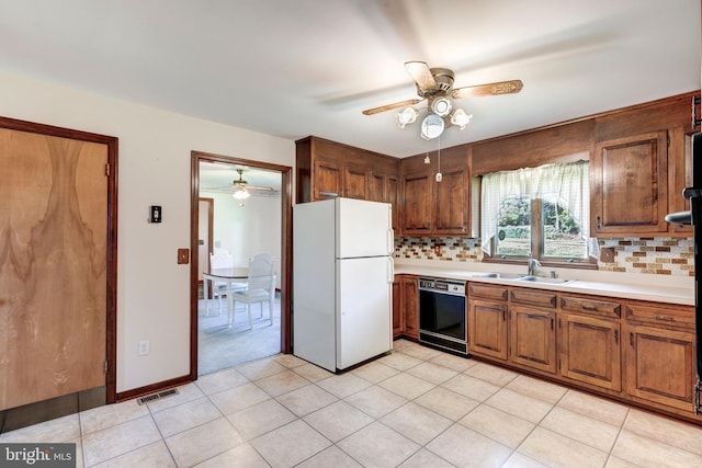 kitchen with black dishwasher, sink, white fridge, decorative backsplash, and light tile patterned floors