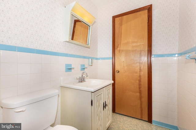 bathroom with toilet, vanity, and tile walls