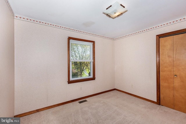 unfurnished bedroom with a closet and light colored carpet