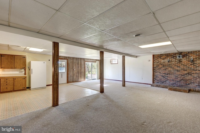 basement featuring light carpet, a drop ceiling, and white refrigerator