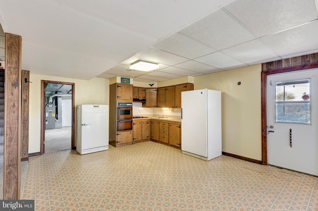 kitchen with a paneled ceiling, stainless steel double oven, and white refrigerator