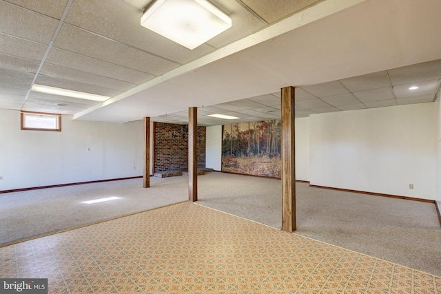 basement featuring a paneled ceiling and carpet flooring