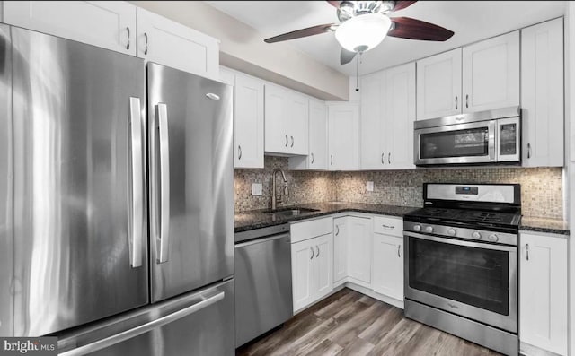 kitchen with sink, appliances with stainless steel finishes, dark wood-type flooring, and white cabinetry