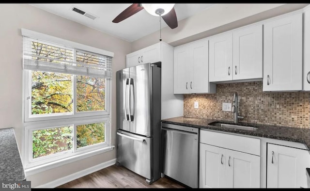 kitchen featuring white cabinetry, stainless steel appliances, dark stone counters, and a healthy amount of sunlight