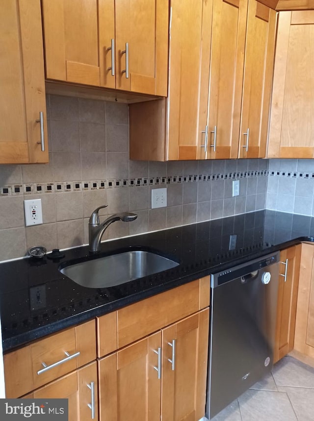 kitchen with stainless steel dishwasher, light tile patterned floors, backsplash, and dark stone countertops