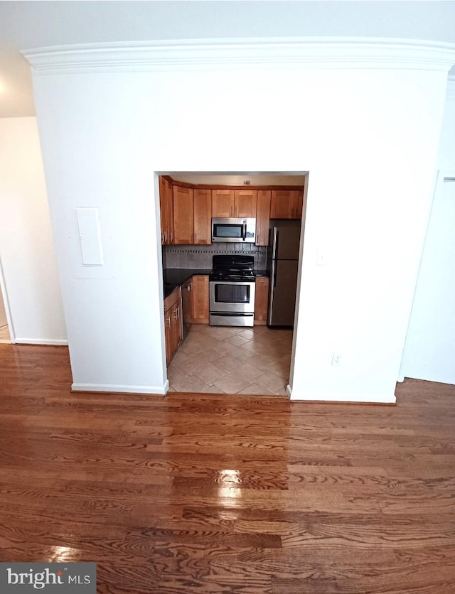 kitchen with crown molding, dark hardwood / wood-style floors, appliances with stainless steel finishes, and decorative backsplash