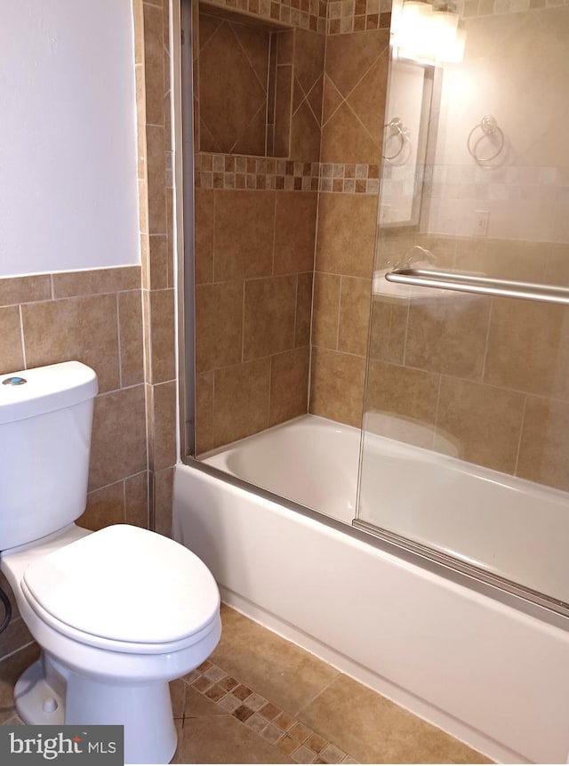 bathroom featuring toilet, tile walls, shower / bath combination with glass door, and tile patterned flooring