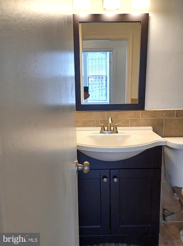 bathroom with vanity, toilet, and tasteful backsplash