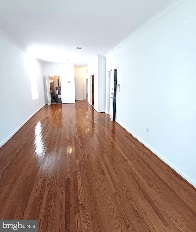 unfurnished living room featuring dark wood-type flooring and crown molding