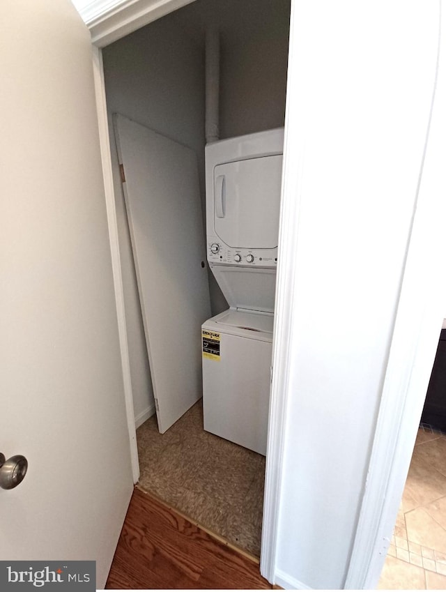 laundry area with hardwood / wood-style floors and stacked washer and clothes dryer