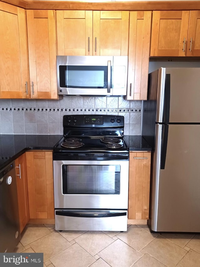 kitchen with appliances with stainless steel finishes, light tile patterned flooring, and decorative backsplash