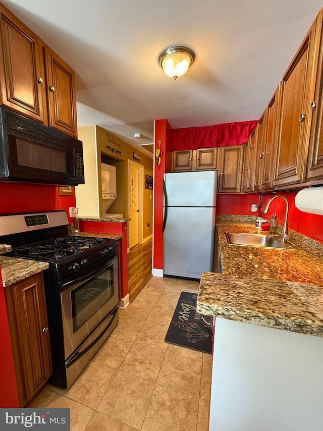 kitchen featuring light stone counters, sink, light tile patterned floors, and stainless steel appliances