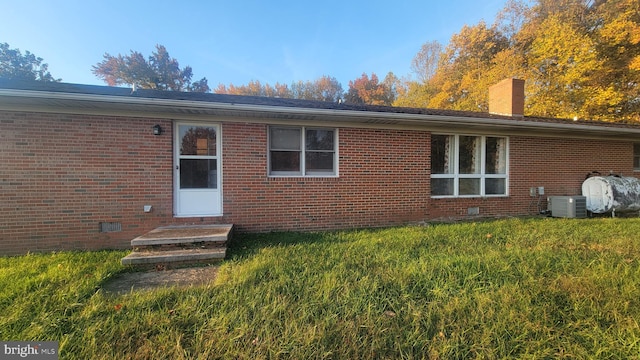 back of property with a yard and central AC unit