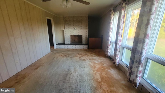 unfurnished living room featuring ceiling fan, ornamental molding, and a fireplace