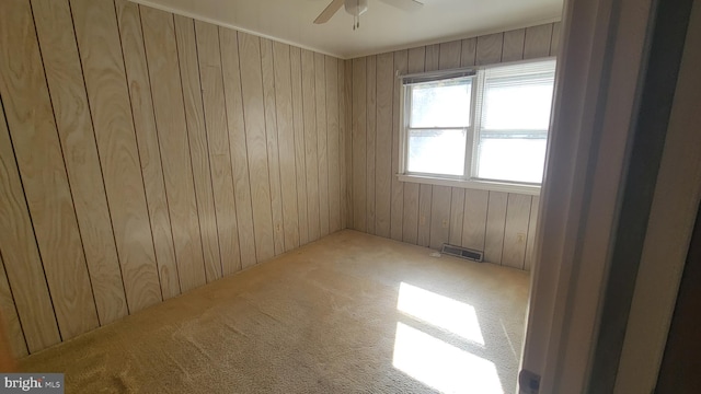 carpeted empty room with ceiling fan and wooden walls