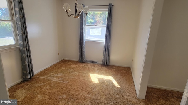 carpeted spare room featuring a notable chandelier