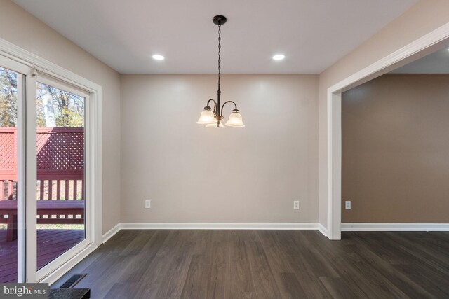 unfurnished dining area with a notable chandelier and dark hardwood / wood-style floors