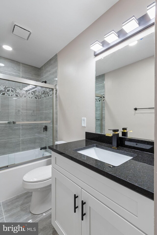 full bathroom featuring combined bath / shower with glass door, vanity, and toilet