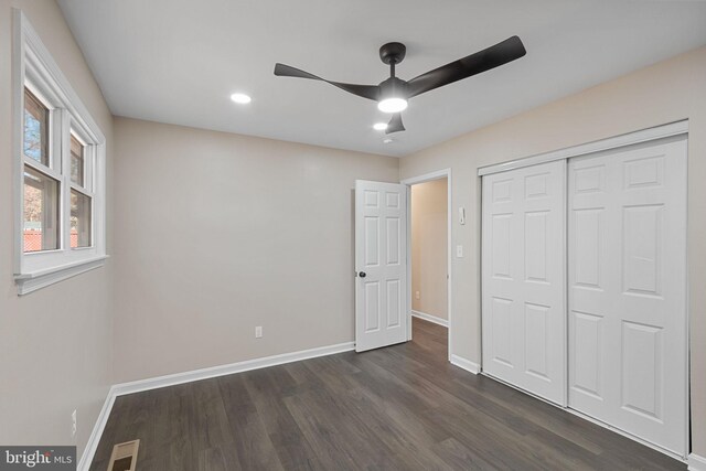 unfurnished bedroom featuring dark wood-type flooring, ceiling fan, and a closet