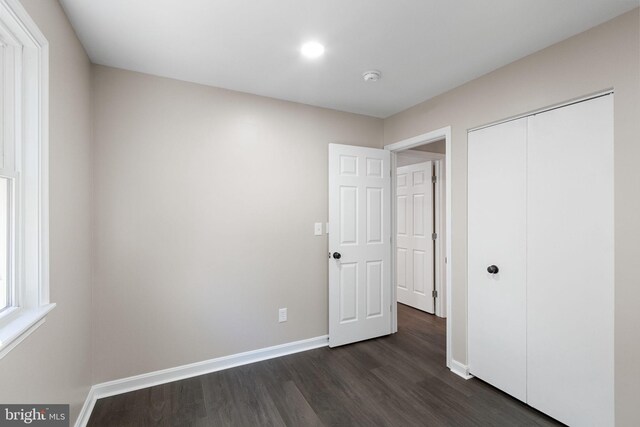 unfurnished bedroom featuring a closet and dark hardwood / wood-style floors