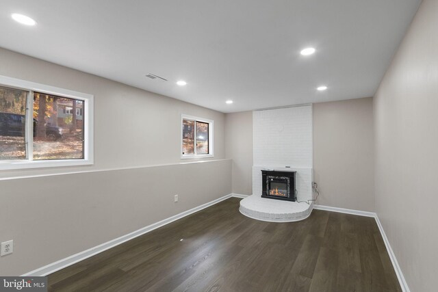 unfurnished living room featuring dark hardwood / wood-style flooring and a brick fireplace