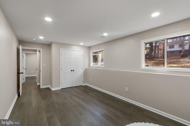 unfurnished bedroom with dark hardwood / wood-style flooring, multiple windows, and a closet