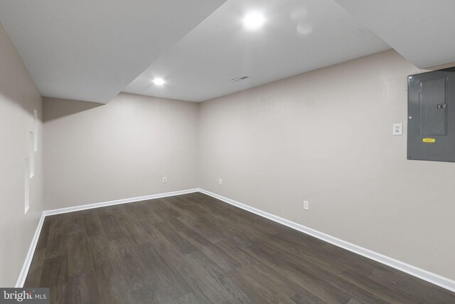 basement with dark wood-type flooring and electric panel