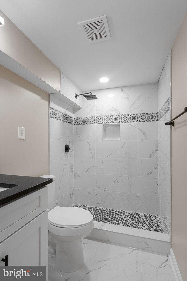 bathroom featuring toilet, vanity, and tiled shower