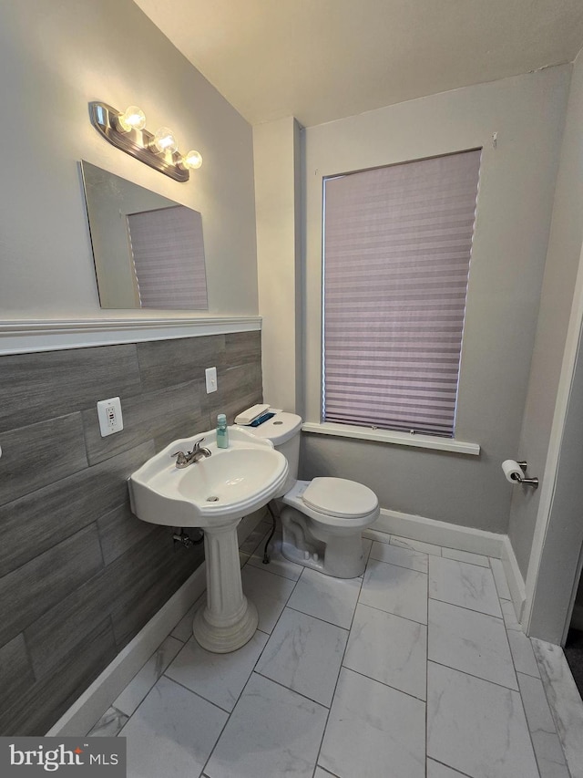 bathroom featuring toilet, tile walls, and sink