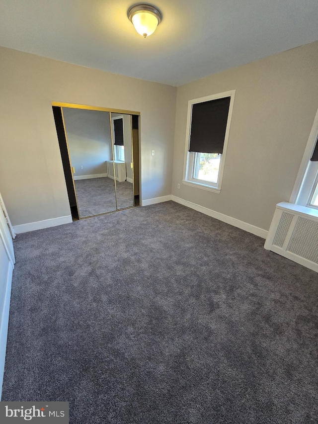 unfurnished bedroom featuring dark carpet and a closet