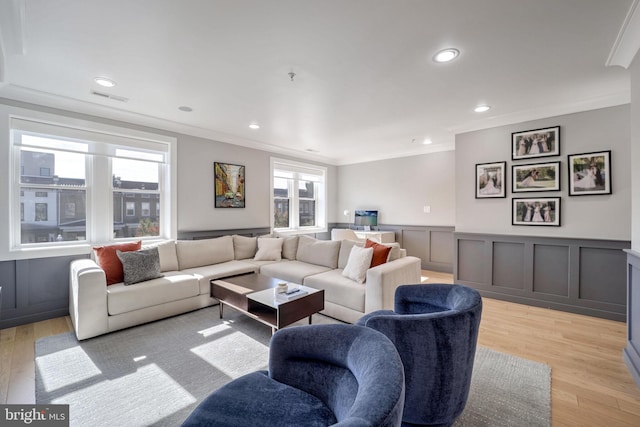 living room featuring light hardwood / wood-style floors, a healthy amount of sunlight, and crown molding